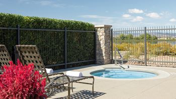 a jacuzzi and two chairs on a patio next to a pool
